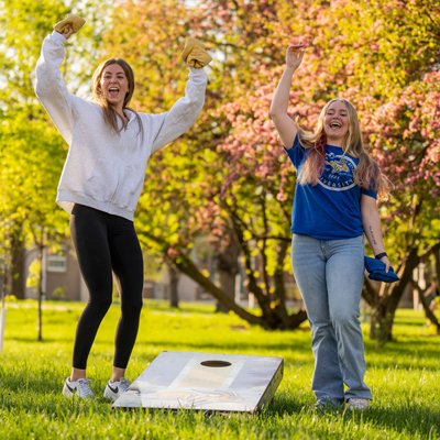 Two students celebrating a good toss for their bean bag toss game held being played on the campus green