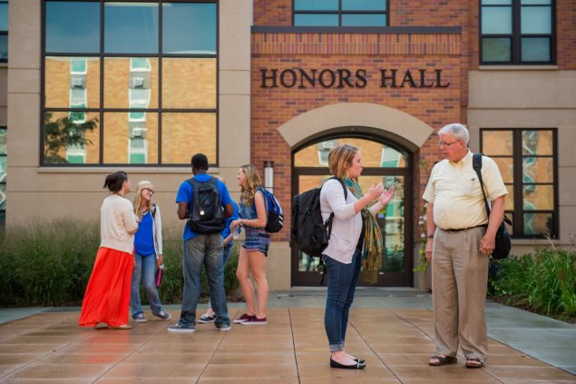 faculty and students talking in the courtyard of the Honors Hall building