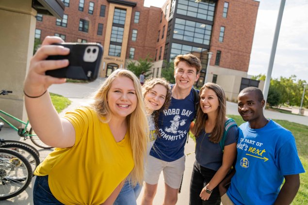 Group of students taking a group photo using a cell phone.